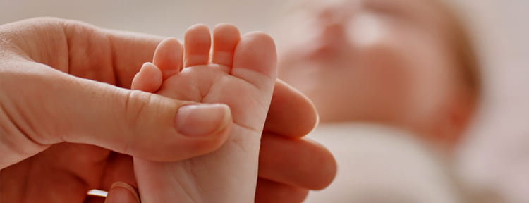 photo of woman's hand holding newborn baby's foot