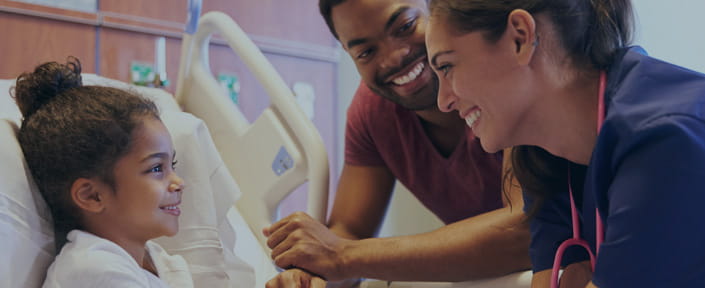 photo of little girl in hospital bed with her father & a nurse at her bedside