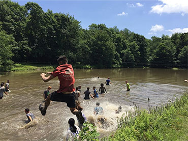 Young male jumping into water.