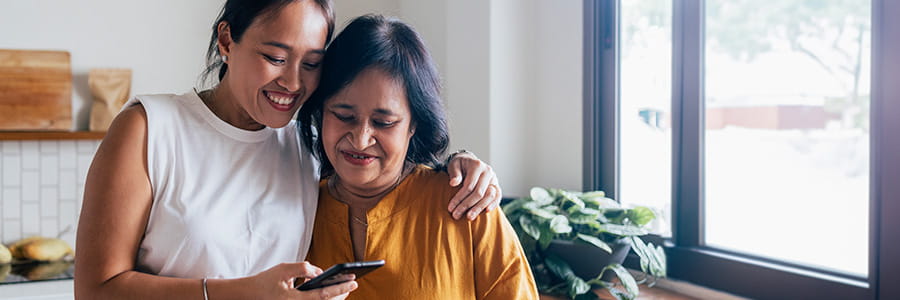 Image of two women hugging while looking at phone.