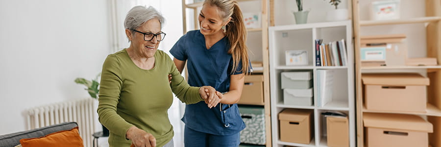 Image of nurse helping an older woman walk.