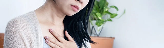 "Common Reasons for Shortness of Breath" article image. Image of woman holding chest.
