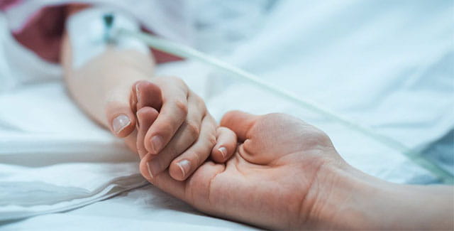Patient and family member holding hands.