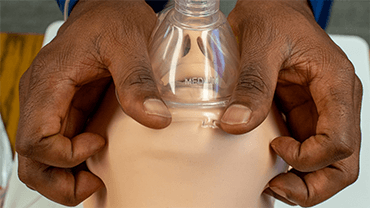Image of hands putting mask on dummy.