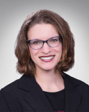 Dr. Kristin Juhasz has shoulder length brown hair. She wears glasses. She is smiling.