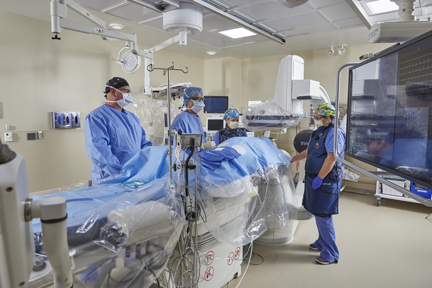 Image of a catheterization lab with 4 medical professionals providing treatment. 