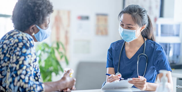 A woman sits at a table with her female healthcare provider. Learn more about breast cancer awareness.