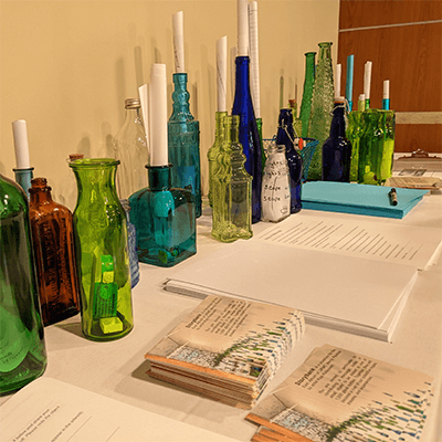 Various bottles and messages on the artist's workstation before assembling them to be hung.