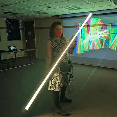 The artist holds her custom designed LED-light stick, standing in front of the studio used to create these images.