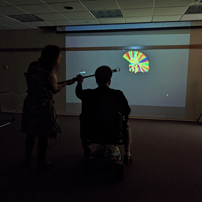 A participant waves the LED light stick, creating multicolored patterns of light that shine brightly in red, blue, yellow and green against the dark background.
