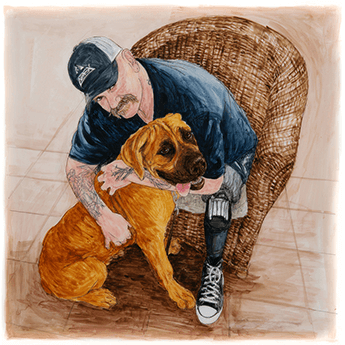 Kevin sits in a wicker chair, leaning forward with his arms around his dog. 