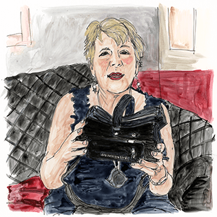Patty Azocar sits on a black sofa holding adaptive goggles.   