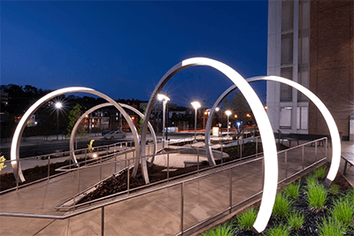 The eight phases of the moon are represented as 10-foot-tall archways along two paths of the plaza. Each archway is made of stainless steel and acrylic with electronically controlled LED lights. The balance of the two materials in each arch represents a different phase of the moon. The full moon is made mostly of acrylic and LED, while the new moon is made mostly of stainless steel. From dusk to dawn, the lights are on, and one arch emits a brighter light than the others to mark the current Moon phase.