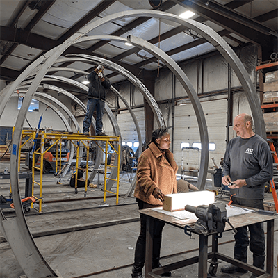 The artist worked closely with KC Fabrications to design, build, and install the sculpture. They both stand in front of the structure during its construction.