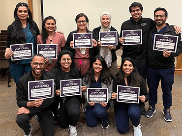 Image of the most recent grads holding up a sign saying, "I Matched".