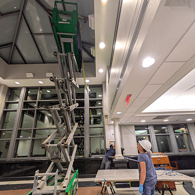 The artist and her team worked together over the course of several nights to install the artwork using a lift. In this photo, they are watching the first branch being suspended from the skylight.