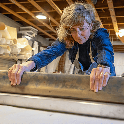 Each artwork includes silk-screened backgrounds and hand painted figures. Sandy demonstrated how she pulls prints in her studio.  Photo by Elan Mizrahi. 