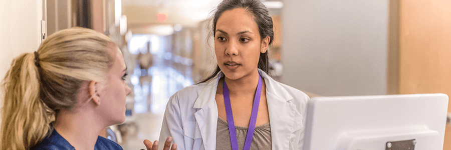 Image of two providers talking in front of monitor.