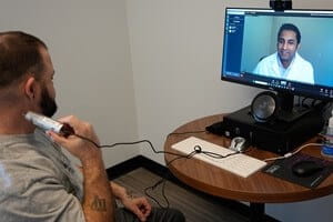 A veteran uses a special camera to provide a zoomed-in view of his skin for the telemedicine physician as part of his examination.