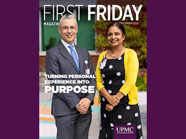 A child and an adult sit at a table covered with colorful building blocks. The adult, wearing a name badge, leans in to engage the child, who raises a hand for a high‑five. The background includes a yellow wall and a cushioned bench, and the scene appears on the cover of First Friday magazine.