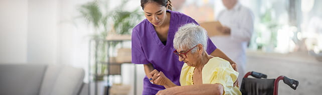 A nurse wearing purple scrubs helps a woman.
