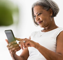 A woman looking at her phone and touching the screen with her pointer finger.