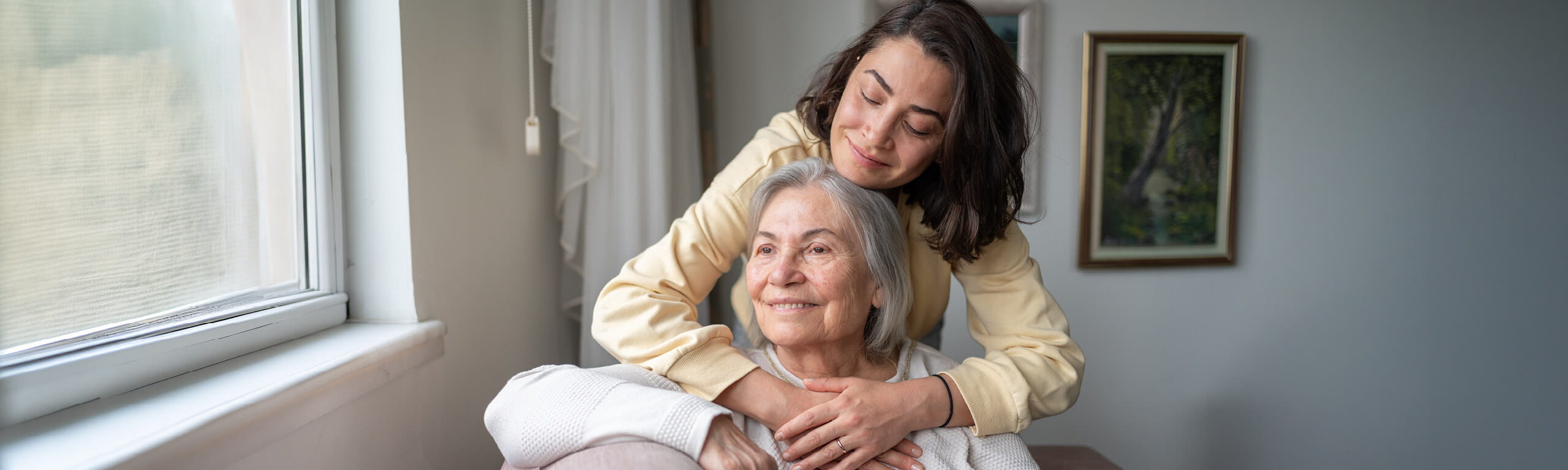 Daughter sitting with arms around older mother