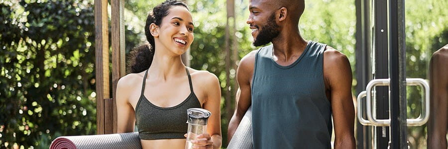 Image of man and woman walking with yoga mats.