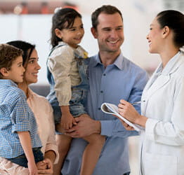 Female family medicine doctor talks to two parents and two children