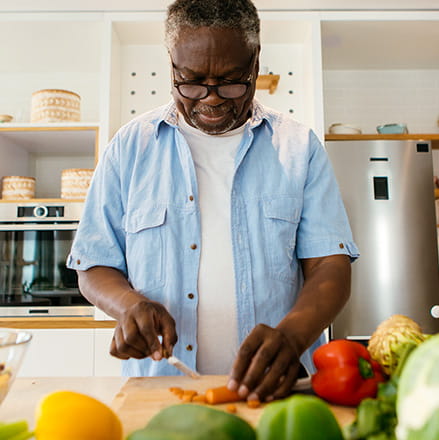 A man dices a carrot on a wooden chopping block. 