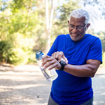 A man in a blue track suit pauses her run to look at the time.
