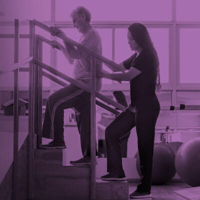 Brain injury rehab image callout. Image of patient walking up steps with therapist behind them.