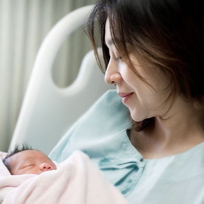 Photo of a woman holding a baby in the hospital.