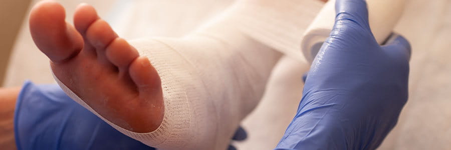 Image of medical professional wrapping a patient's foot with gauze.