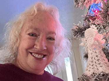 Image of Vicki by her Christmas tree.