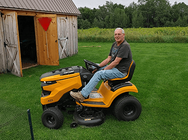Steve Riley on riding lawn mower.